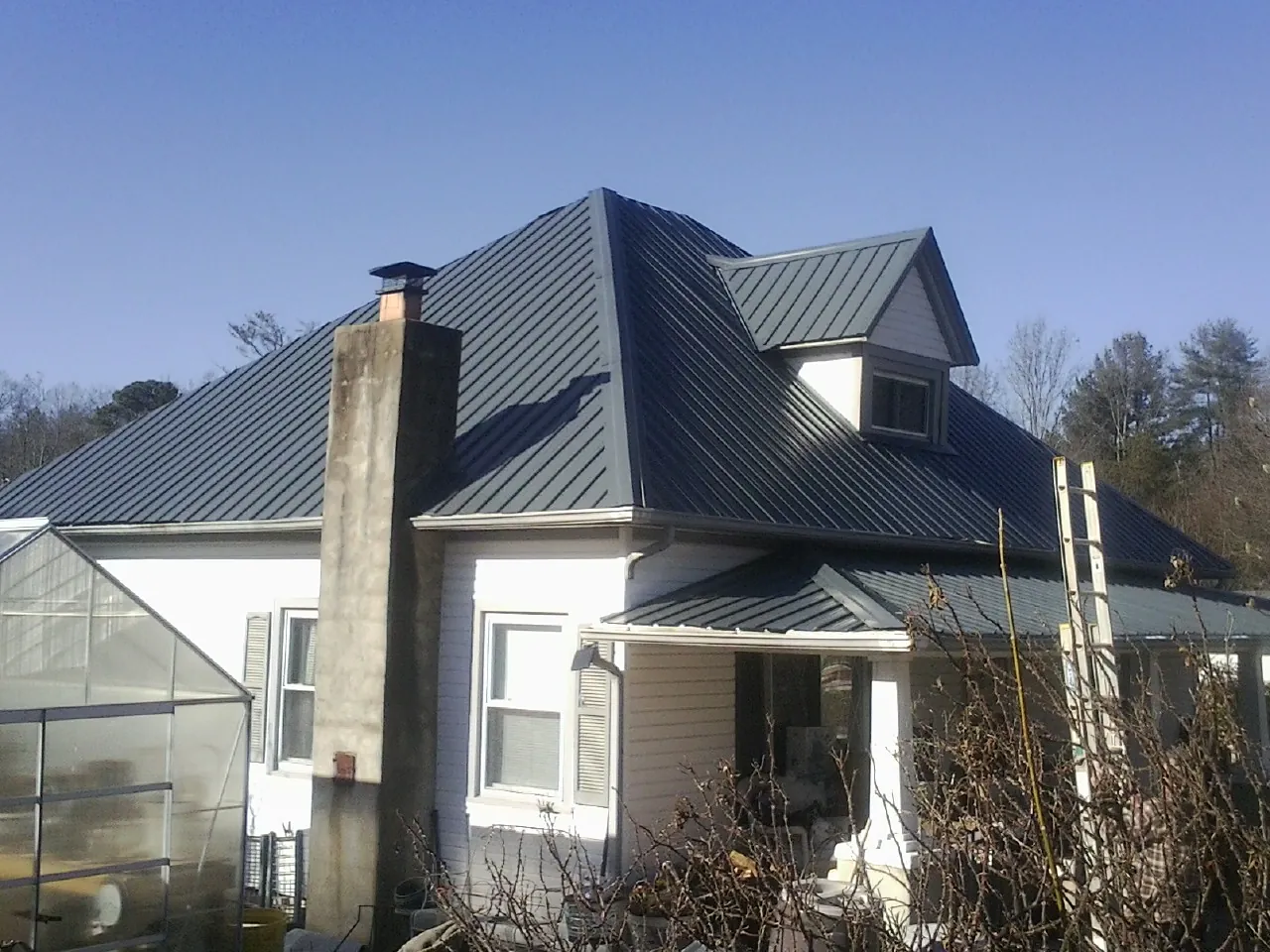 Dark blue standing seam metal roof on a white farmhouse with dormer — Slate & Tile Roof Repair by Roofing Brothers in Sunland