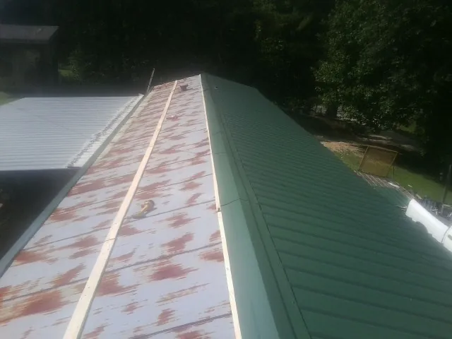 Old rusted panels beside newly installed green metal roofing — Wind Damage Roof Repair by Roofing Brothers in Sunland