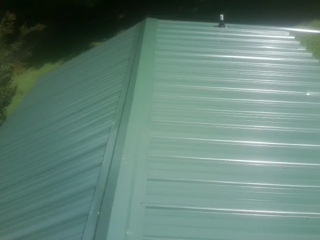New green metal panels meeting at the ridge of a roof — Flat Roof Repair work by our crew in Sunland