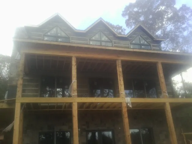 Dormers and porch framing on a large log home under construction — Roof Coating work by our crew in Sunland
