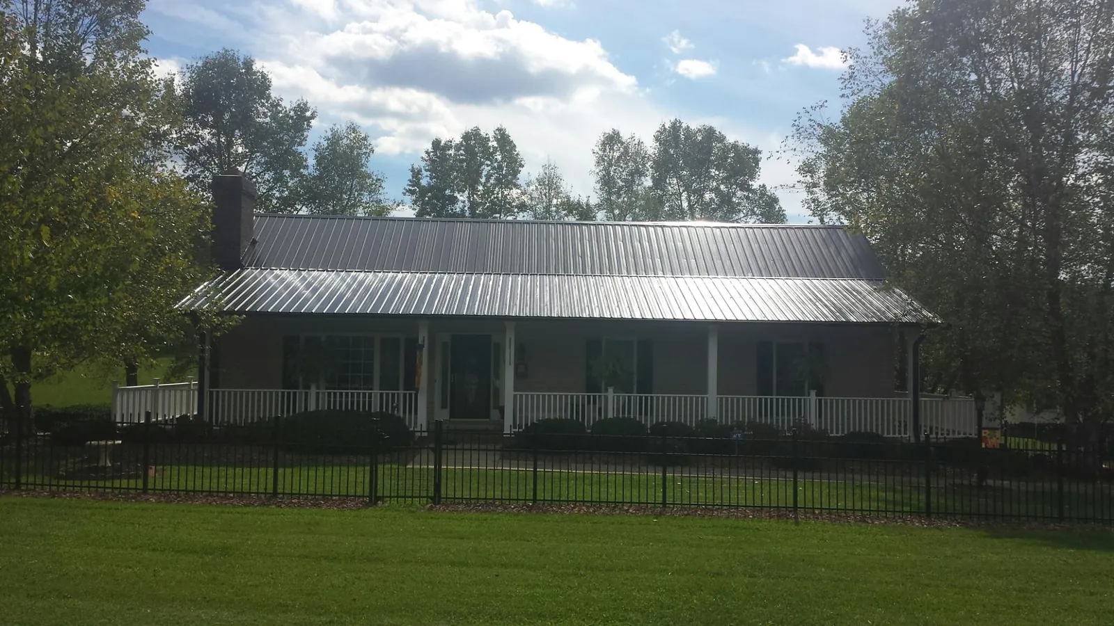 Gray metal roof on a brick ranch with a full width front porch — Gutter Guard Installation work by our crew in Sunland