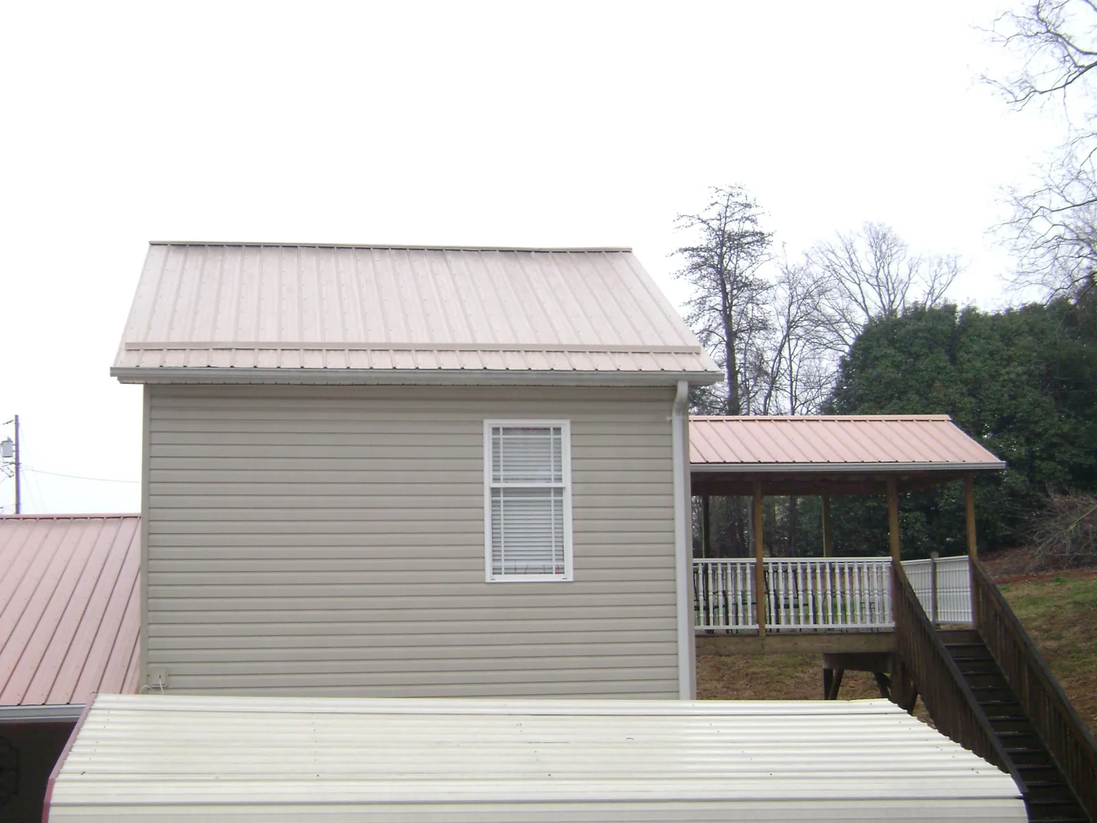 Tan metal roofs on a two story addition and attached porch, from a Roof Replacement job in Sunland